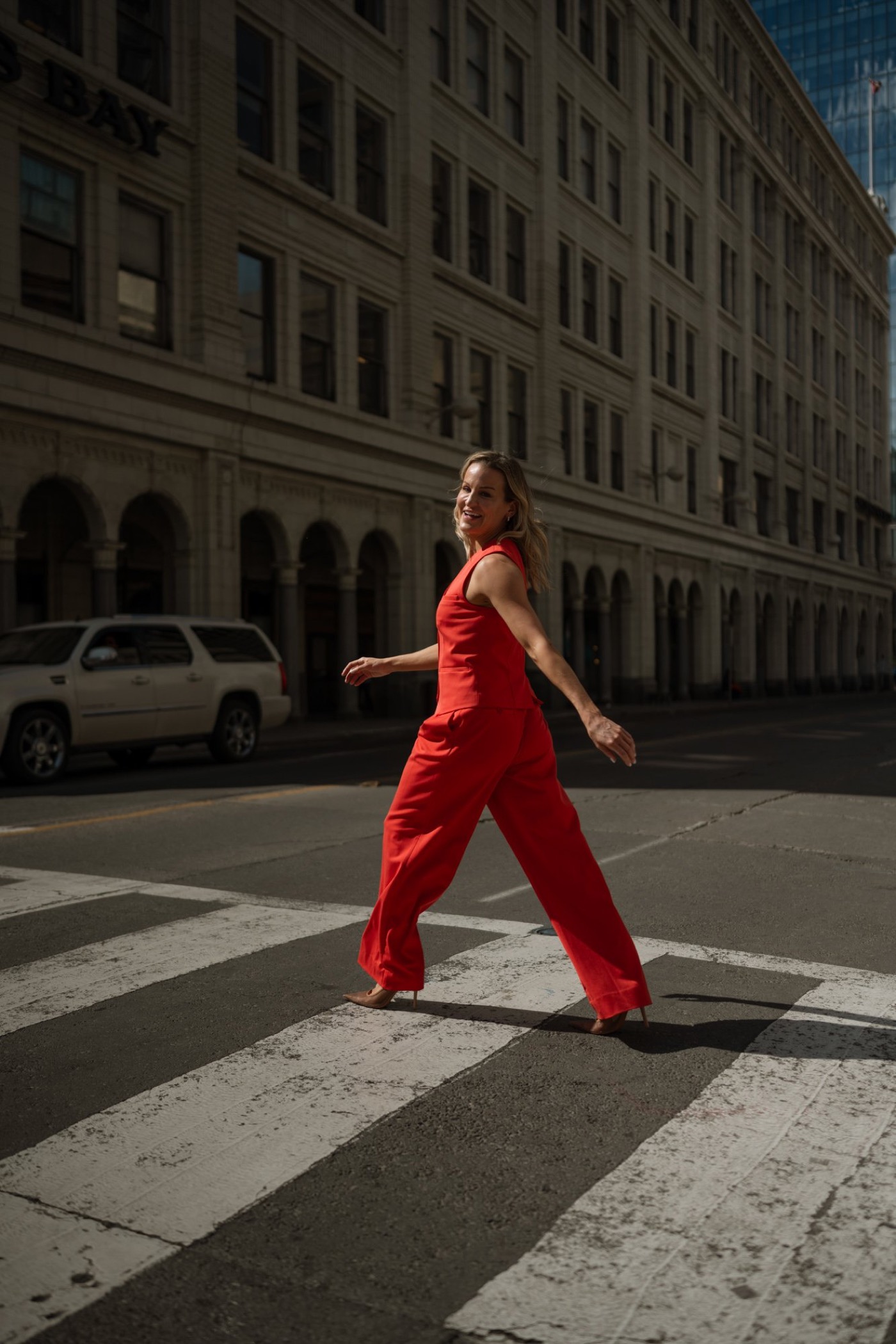 Dr. Marie Claire Bourque walking across a city street in a red suit