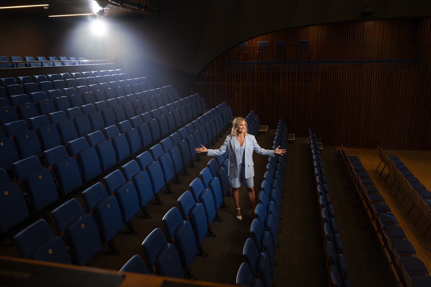 Dr. Marie Claire Bourque with her arms open in the aisle of an empty theatre